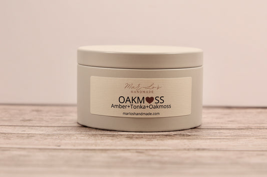 5.5 oz Oakmoss candle tin with wooden wick and clean-burning coconut apricot wax in a reusable metal container; fresh, citrusy, and earthy scent.